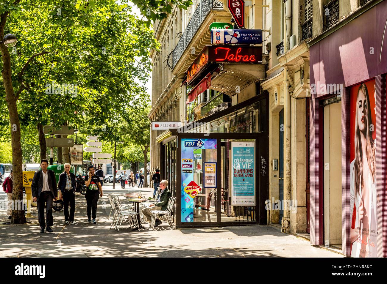 man sitting in a typical bar with tabac shop and winter gardenn at the walk way Stock Photo