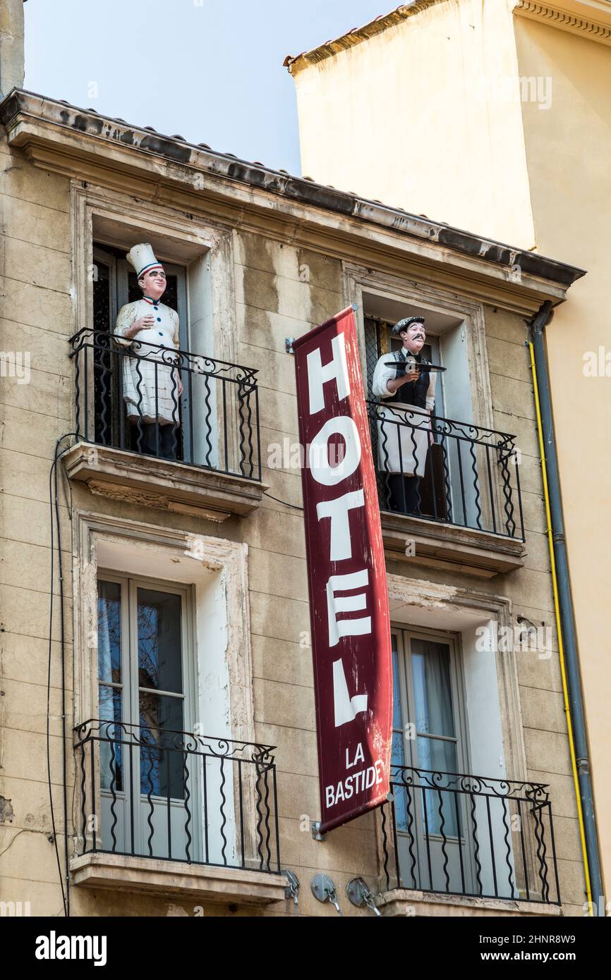 sign Hotel at an old facade in red letters in Aix en Provence and a statue of a cook at the balcony Stock Photo