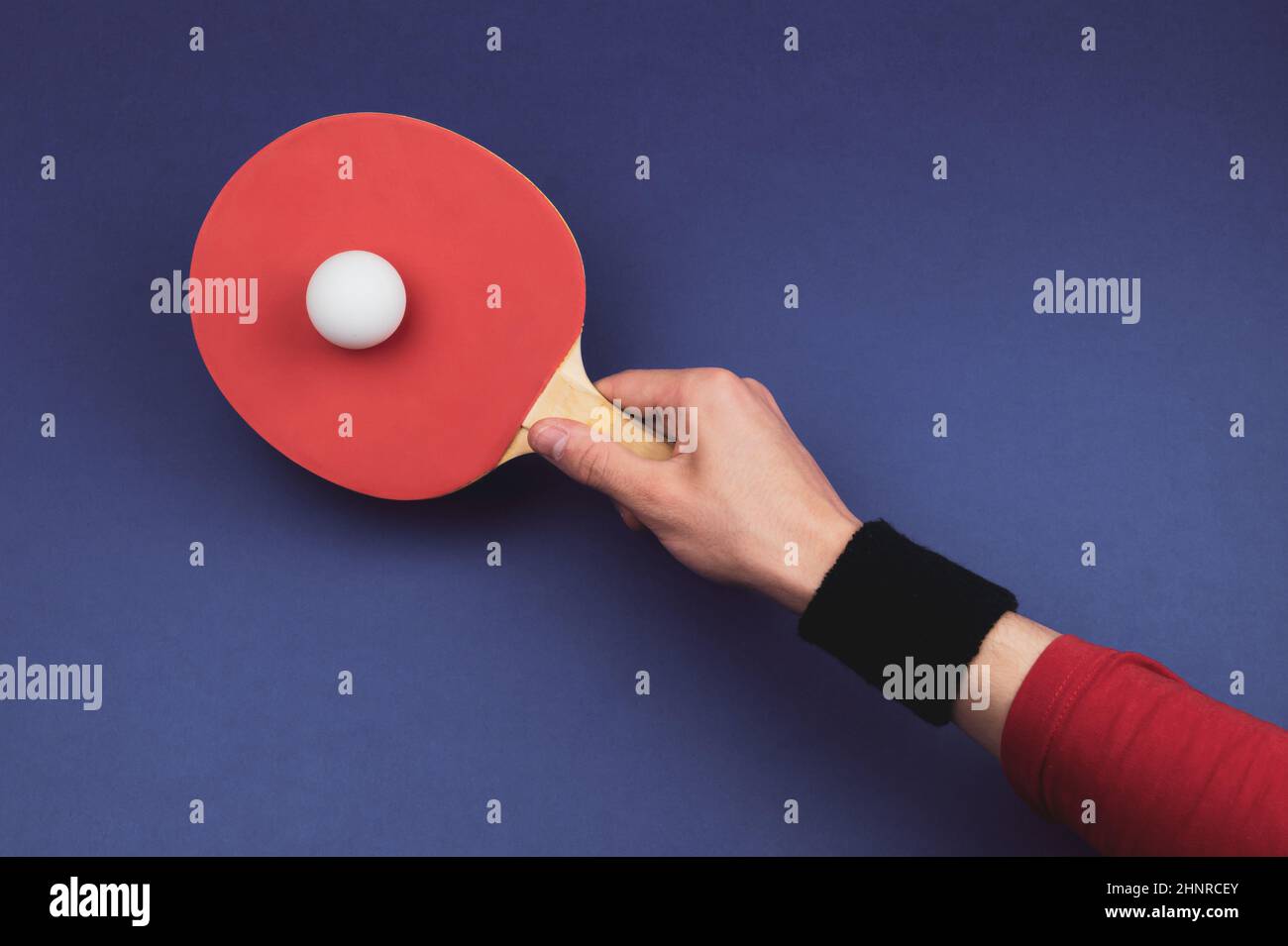 Red table tennis racket in hand. hitting the ball. sport equipment for ping pong. copy space