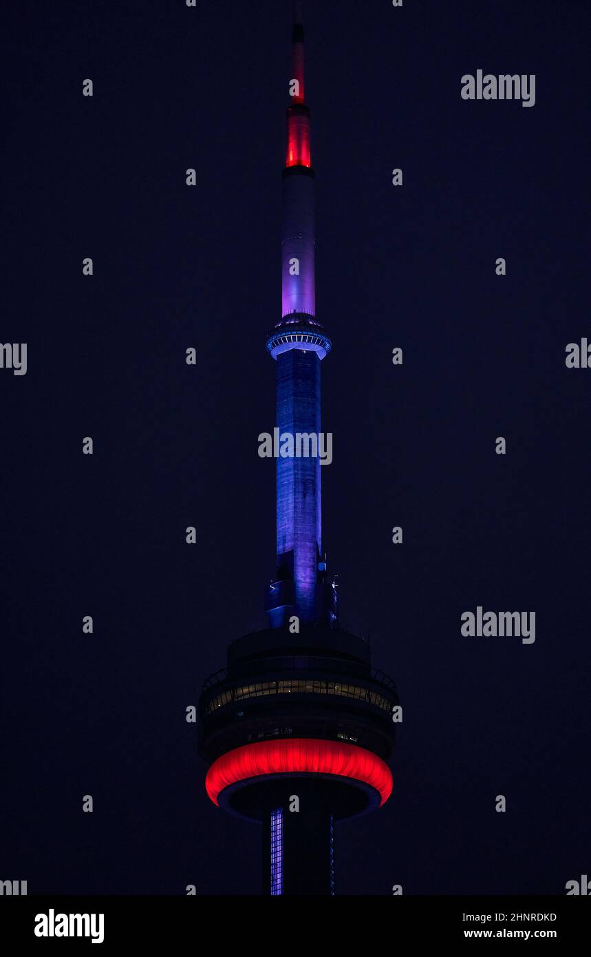 Vertical shot of the illuminated CN tower against a dark sky at night