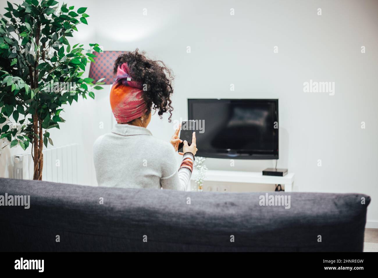 Afro woman using her cell phone in comfort of her home Stock Photo