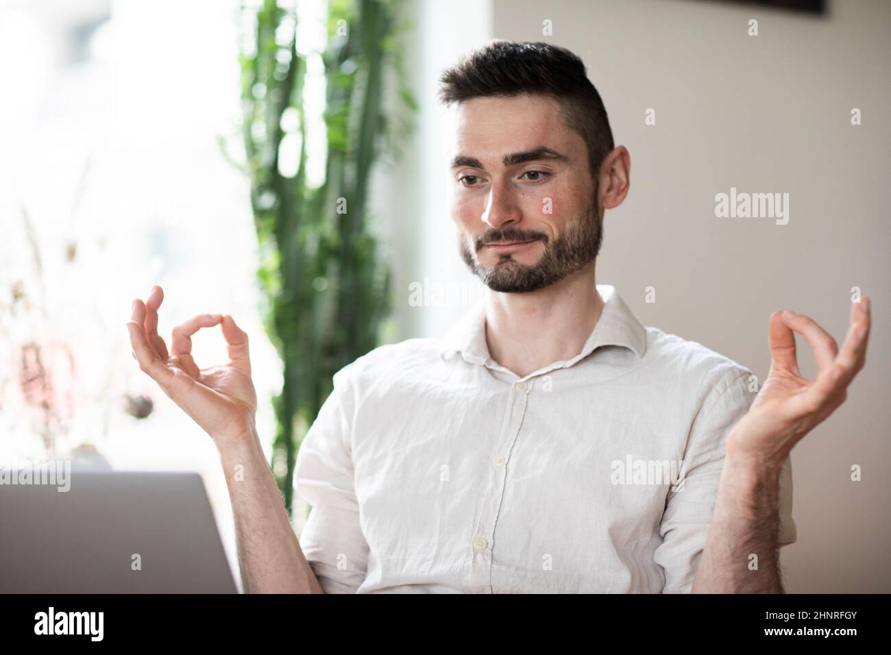 Young man in a room is wellbeing and mindful behind a laptop Stock Photo