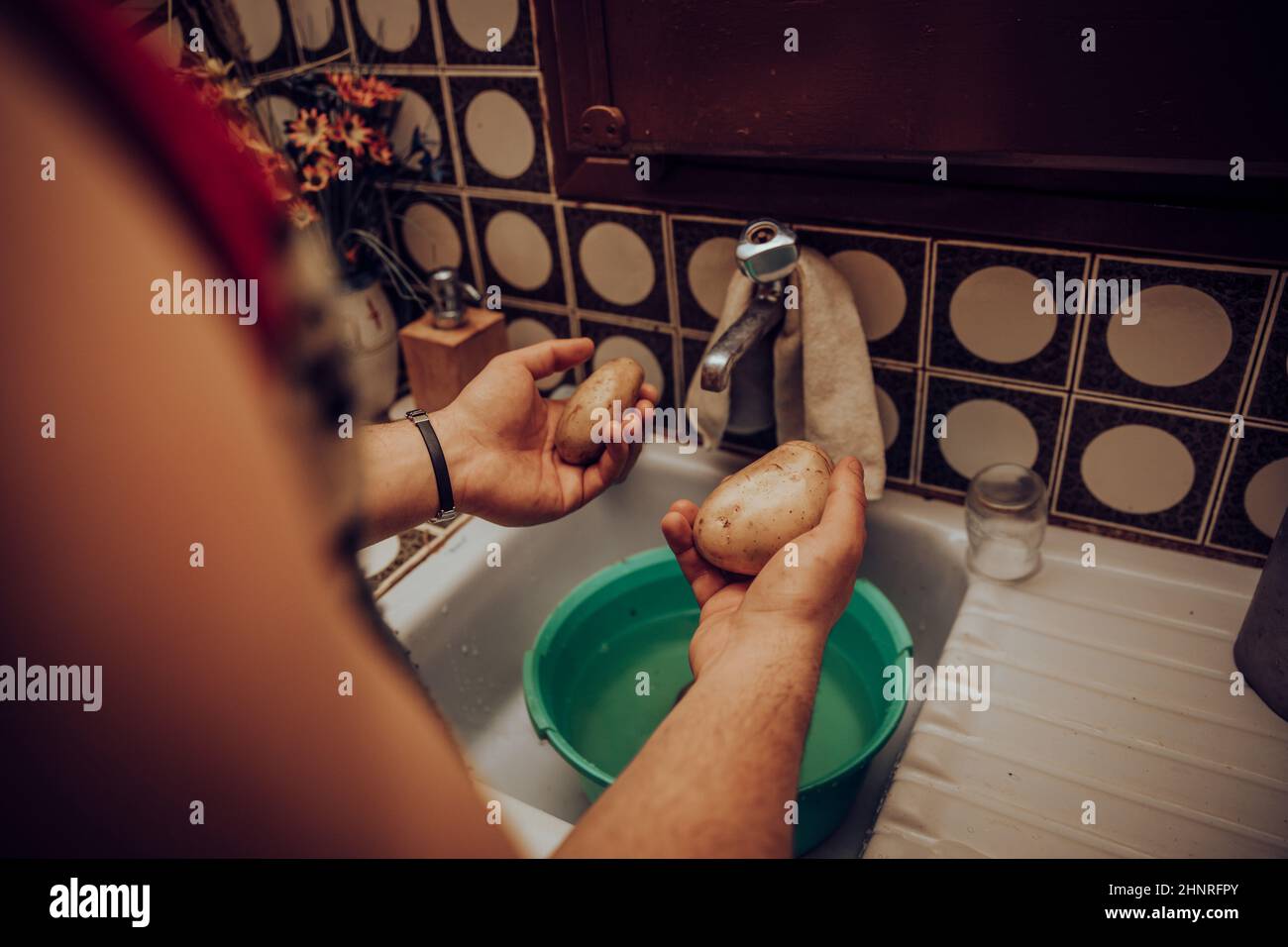 Hands washing potatoes in sink Stock Photo