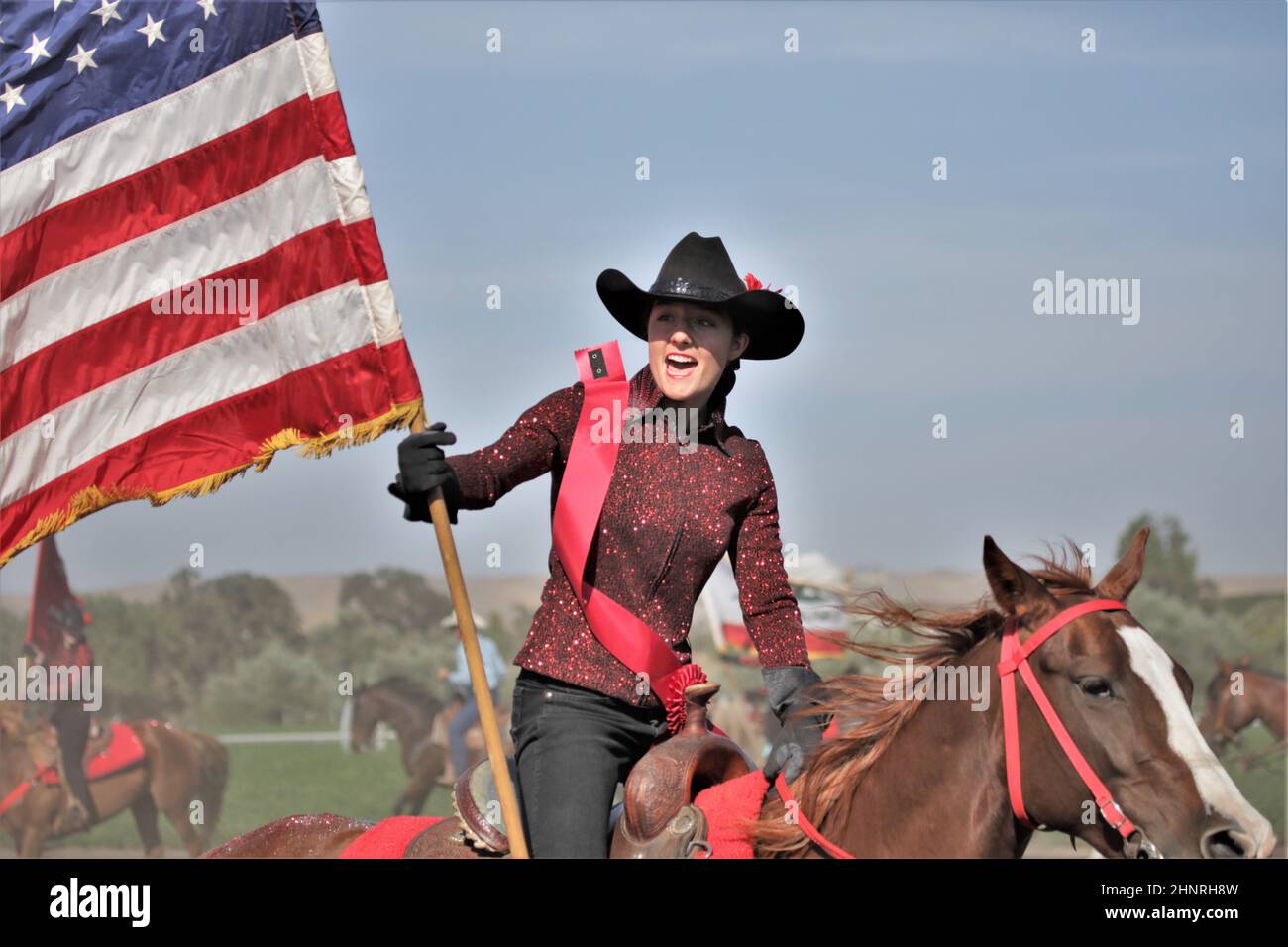 Pretty young woman flag carrier at a local farm rodeo with happy smile on  her face and cowboy hat on her horse and American flag Stock Photo - Alamy