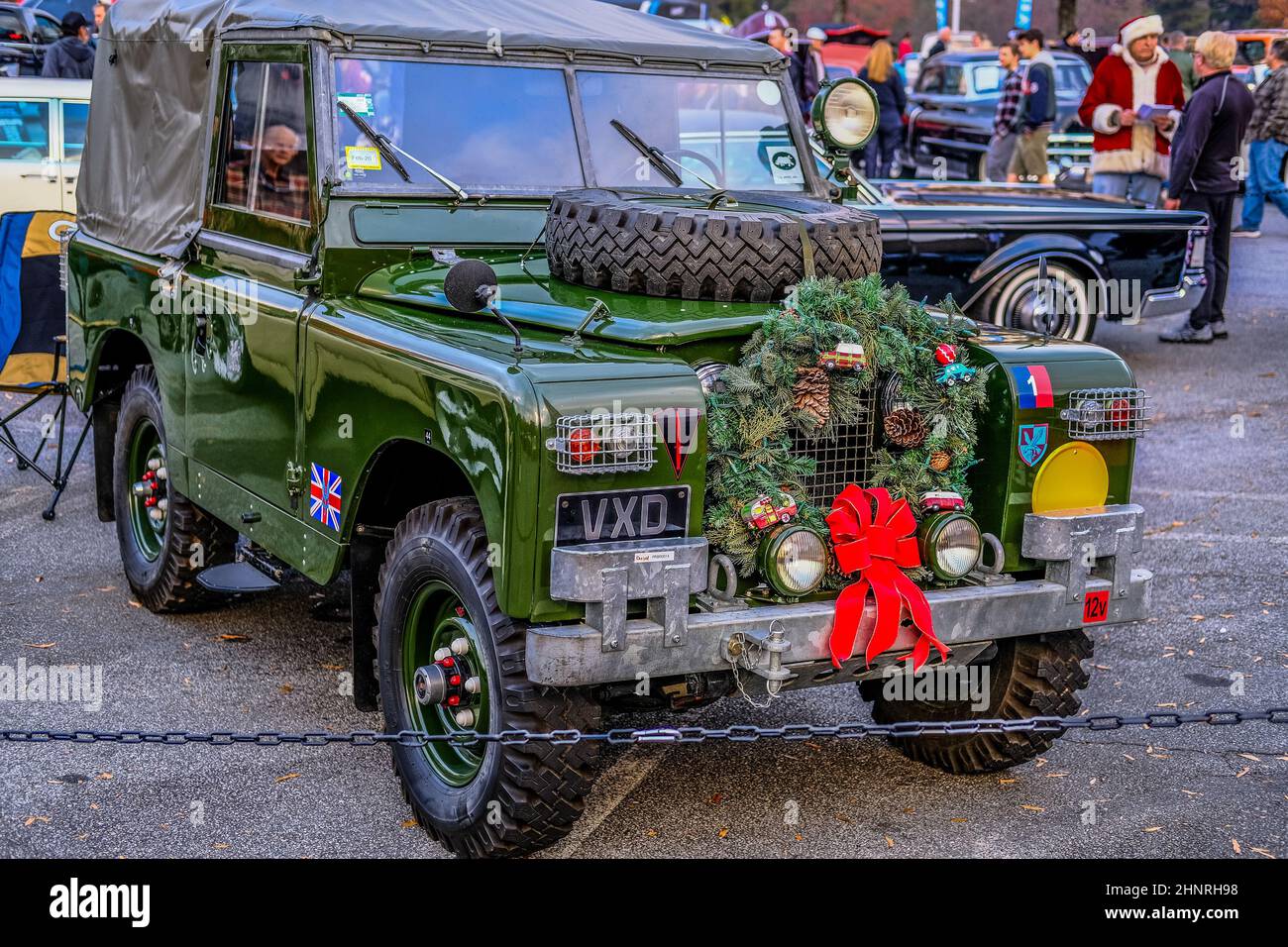 Classic Green Land Rover with Santa Claus in Background Stock Photo