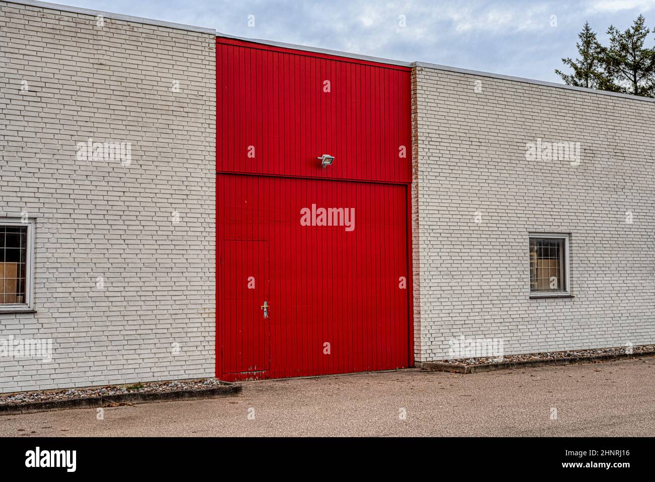 red door and gate on a white brick wall at the front of a storehouse with windows with grids, Frederikssund, Denmark, Februar, 17, 2022 Stock Photo
