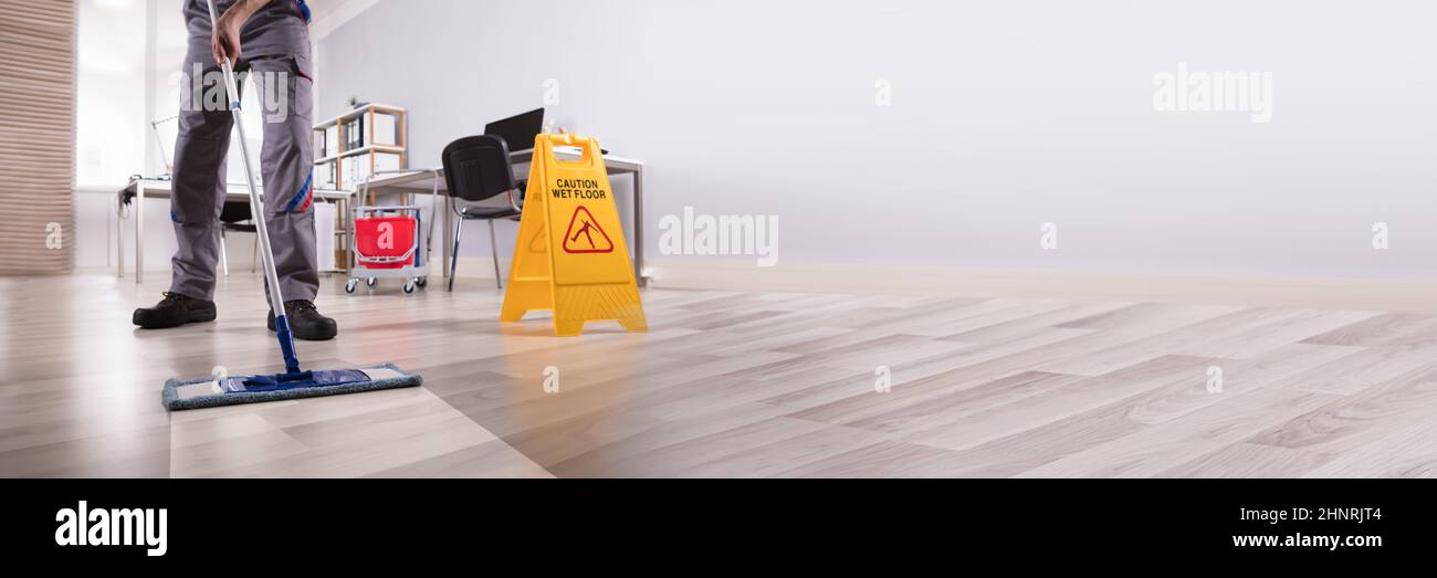 Full Length Portrait Of Happy Female Janitor Mopping Floor In Office Stock Photo