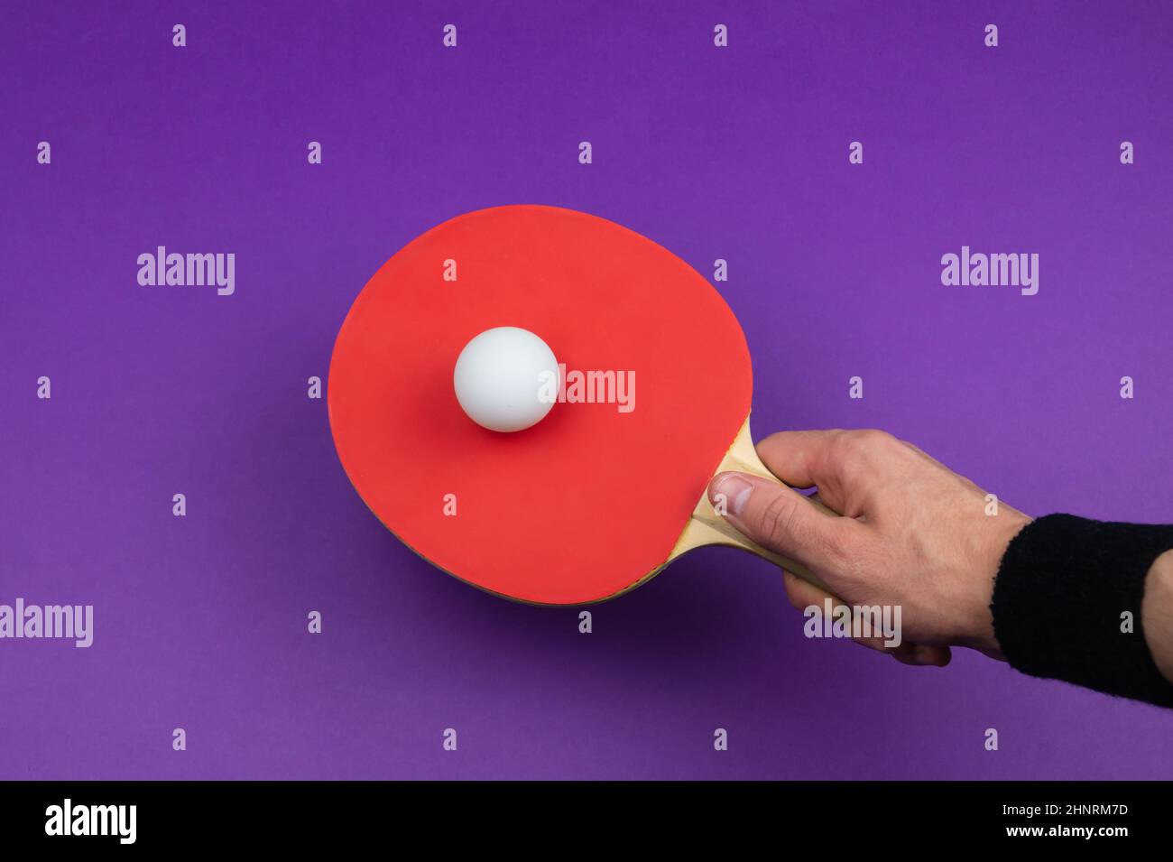 Red table tennis racket in hand. hitting the ball. sport equipment for