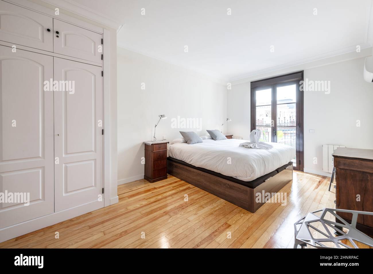 bedroom with a dark wooden bed, white lamps on the bedside tables, a