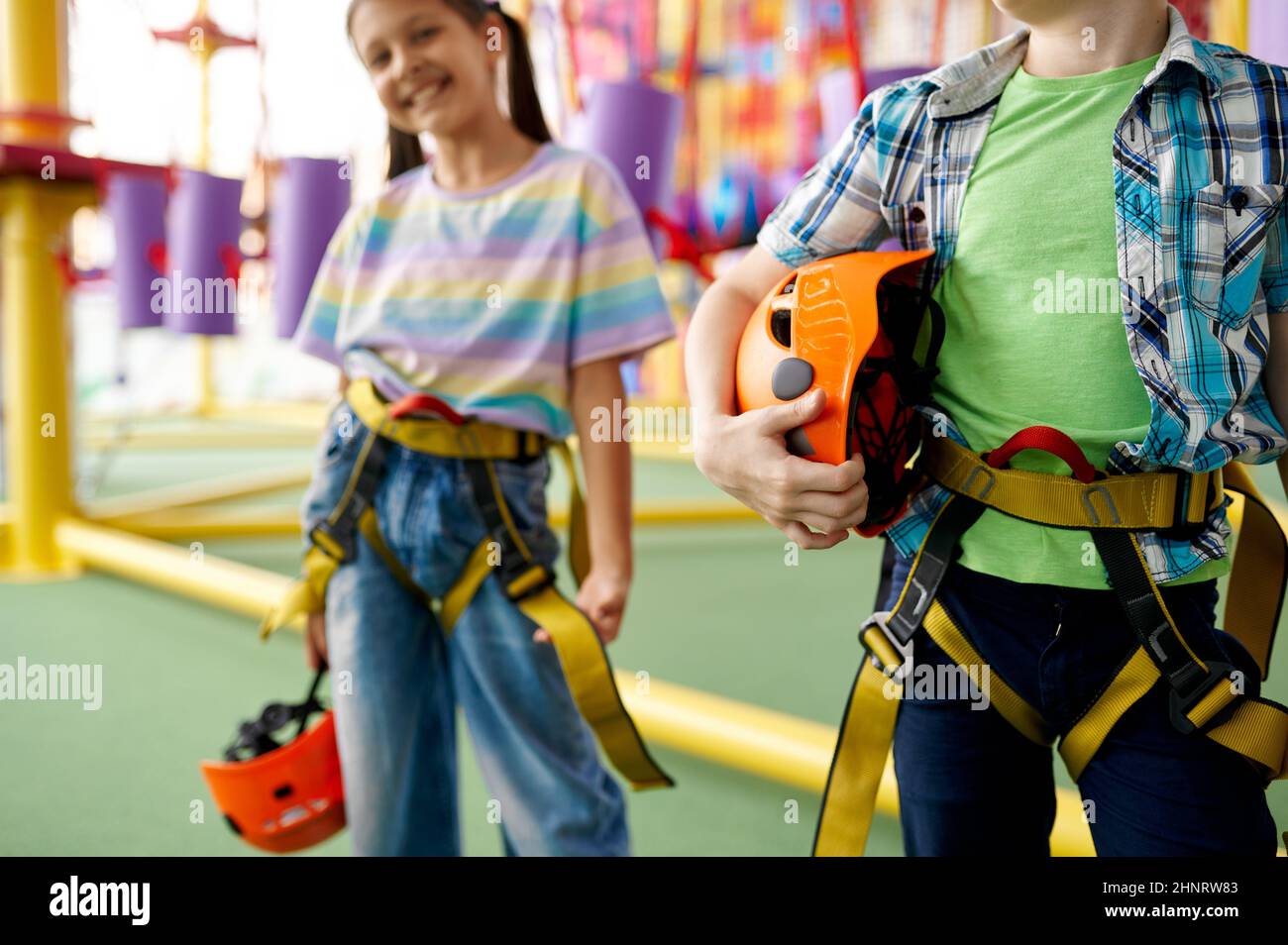 Two children poses in climbing area in entertainment center, young climbers. Boy and girl having fun on ropes, kids spend the weekend on playground, h Stock Photo