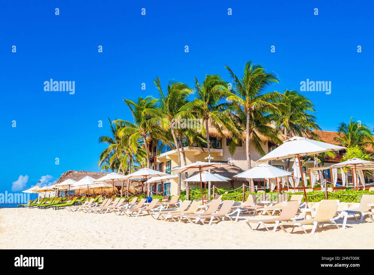Palms parasols sun loungers beach resort Playa del Carmen Mexico. Stock Photo