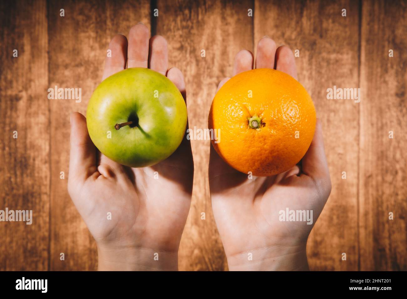 Comparison of apples with oranges. Young female woman holding an apple