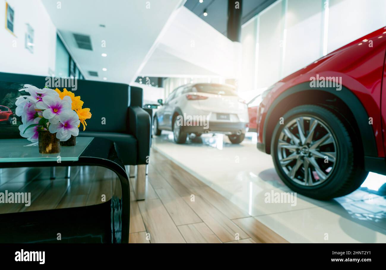 Customer reception area and blur red and white luxury SUV car parked in modern showroom. Car dealership and auto leasing concept. Automotive industry. Showroom interior. New SUV car stock for sale. Stock Photo