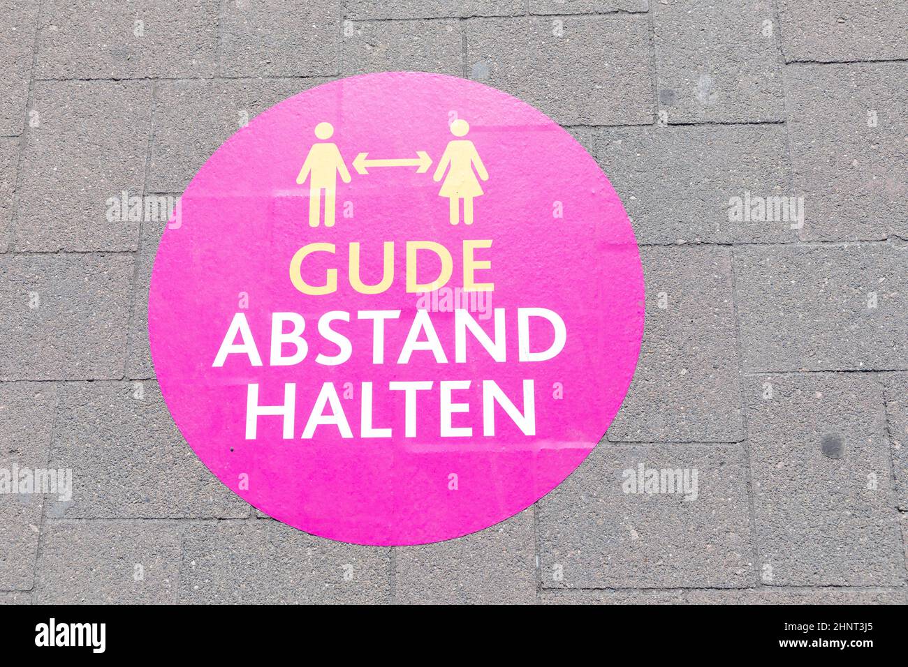 signage keep distande (Abstand halten) at the floor of a pedestrian promenade in Ruedesheim Stock Photo