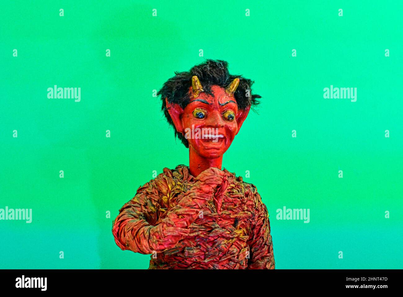 Figure of Krampus or devil. Central European tradition. The Krampus or devil is in the tradition of a fright figure in the company of St. Nicholas. Devil figure on green background Stock Photo