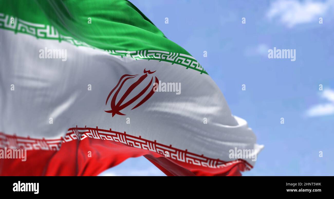Detail of the national flag of Iran waving in the wind on a clear day. Islamic republic. Patriotism. Western asian country. Selective focus. Stock Photo