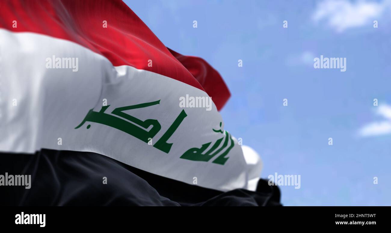 Detail of the national flag of Iraq waving in the wind on a clear day. Democracy and politics. Patriotism. Western asian country. Selective focus. Stock Photo