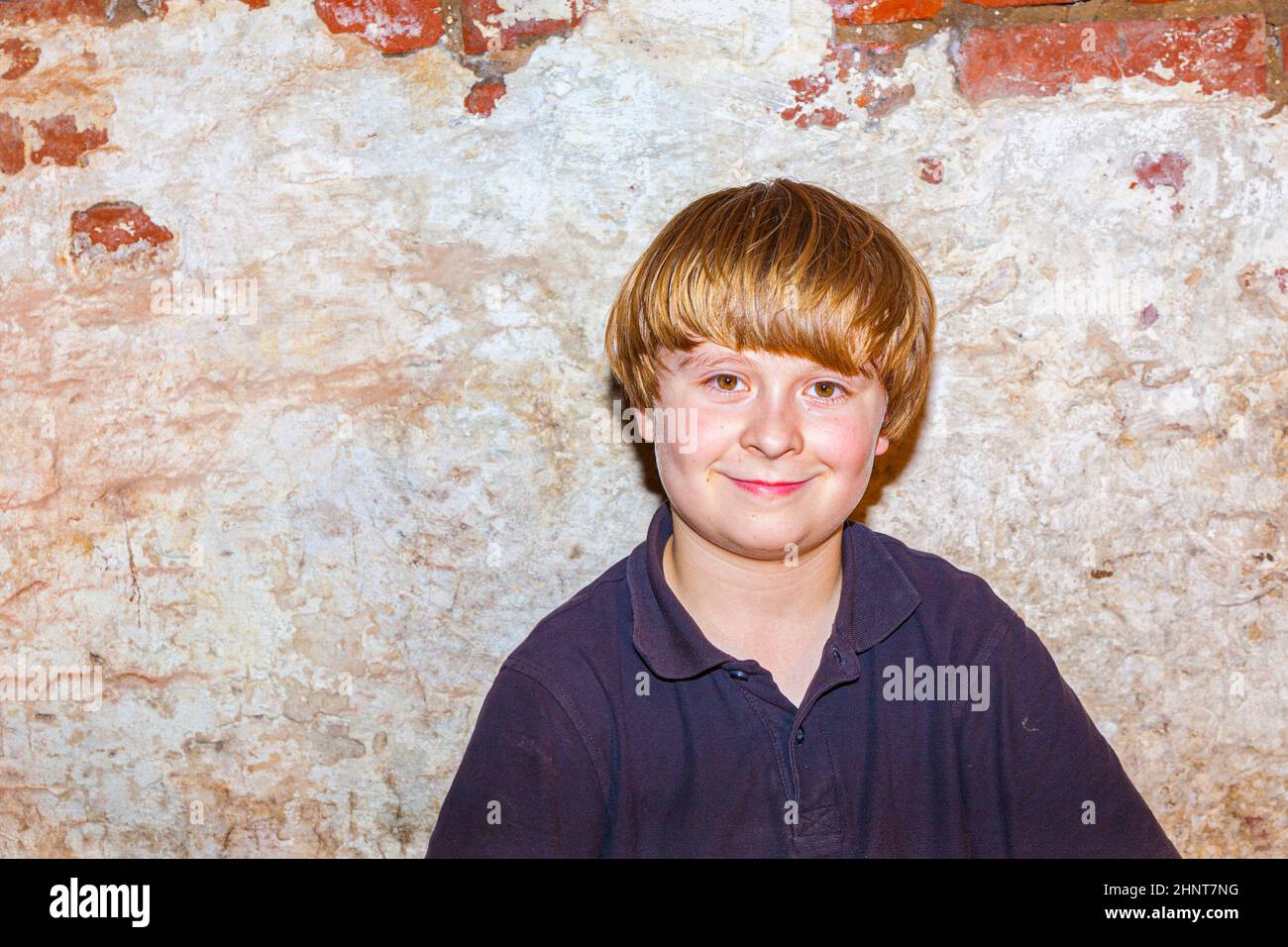 portrait of a cute young boy with old brick wall background Stock Photo ...