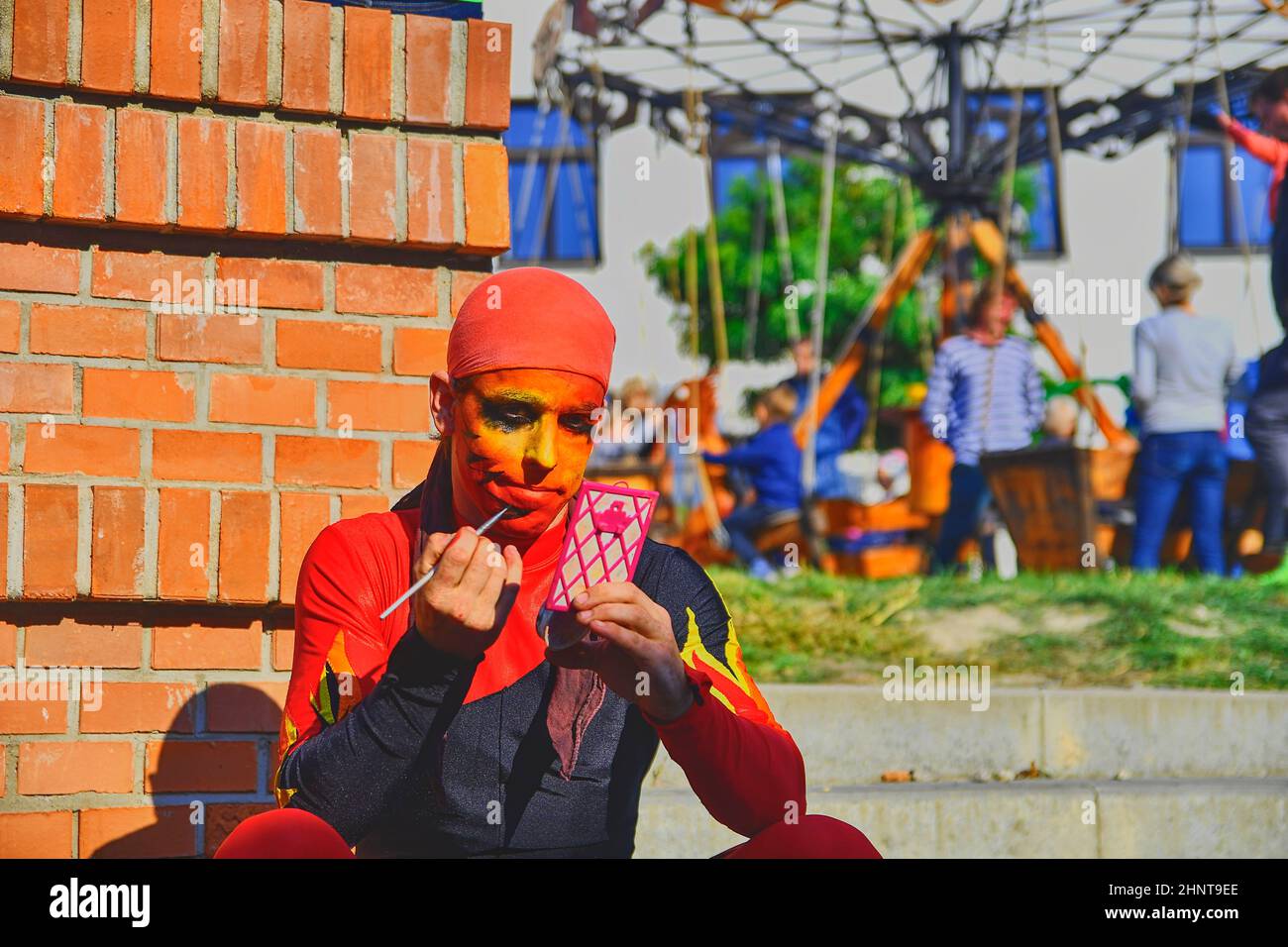 Street performer putting on his face make-up. Street performers can fool passersby and entertain tourists. Stock Photo