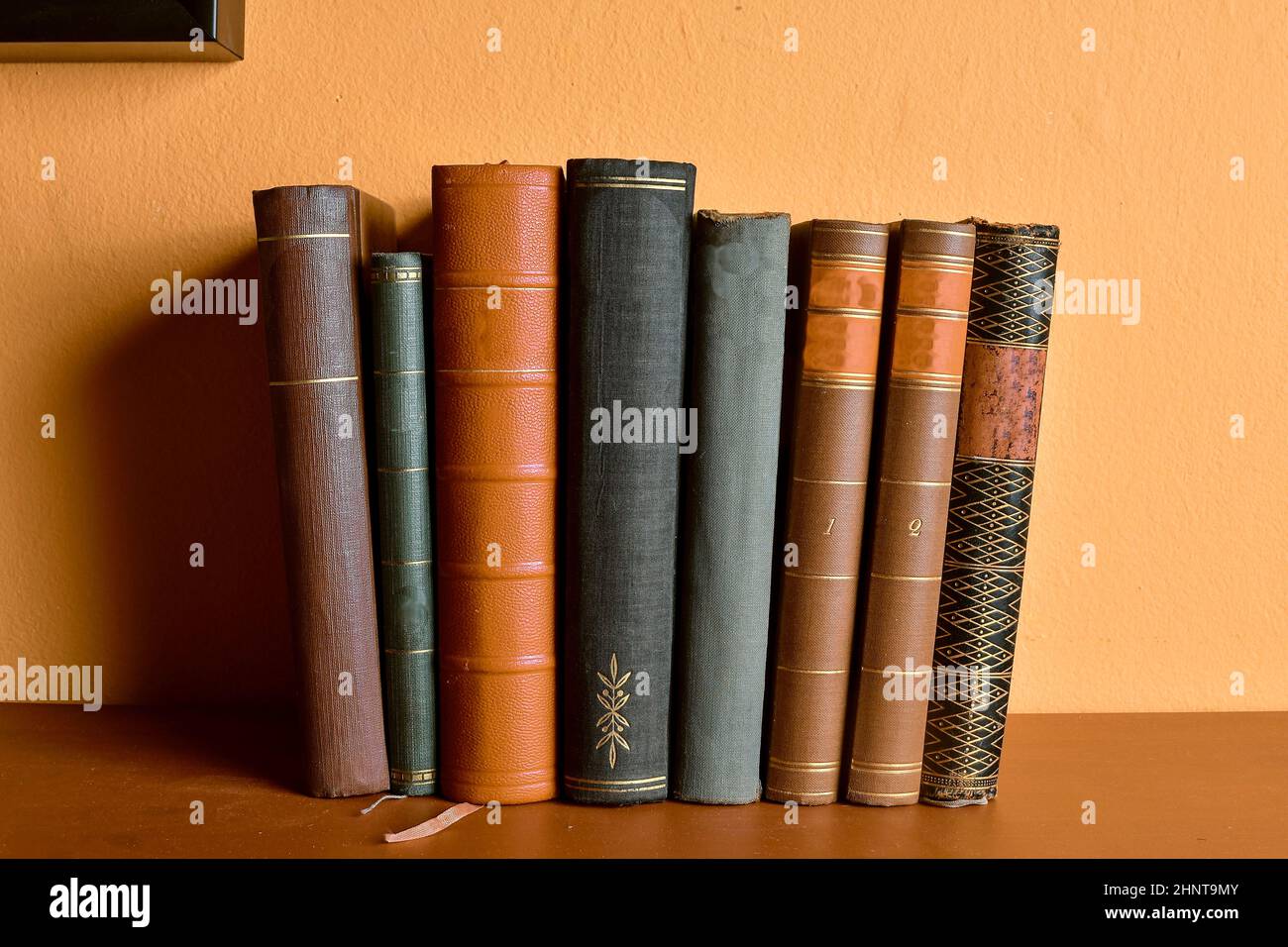 Row of old bound books. Antique books on yellow and claret background Stock Photo