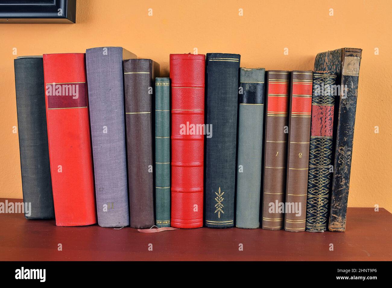 Antique books on old wooden shelf. Old books on yellow and claret background Stock Photo