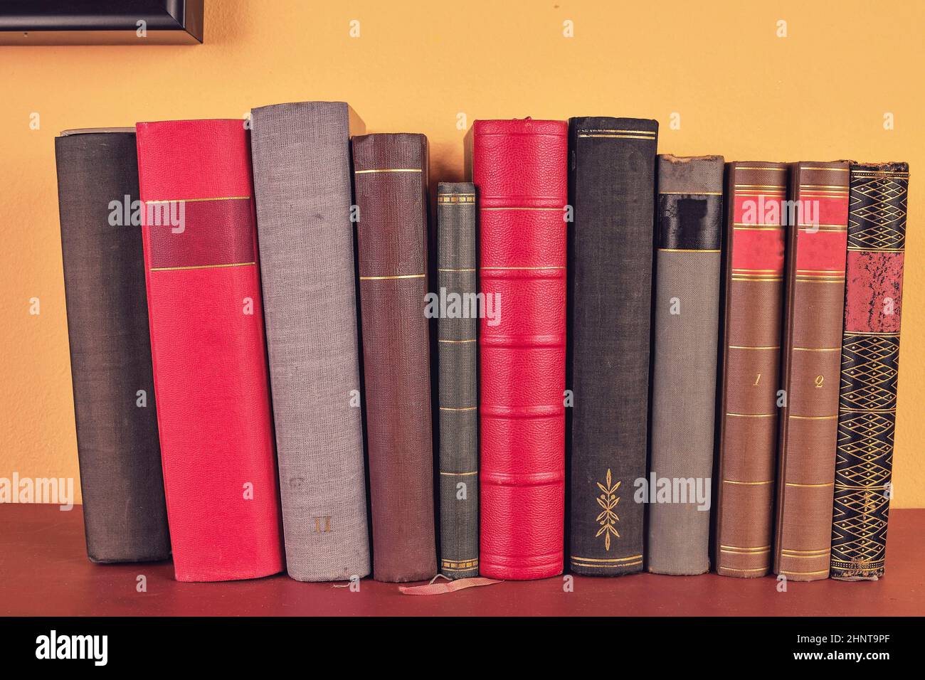 Old books on wooden shelf. Antique books on yellow and claret background Stock Photo
