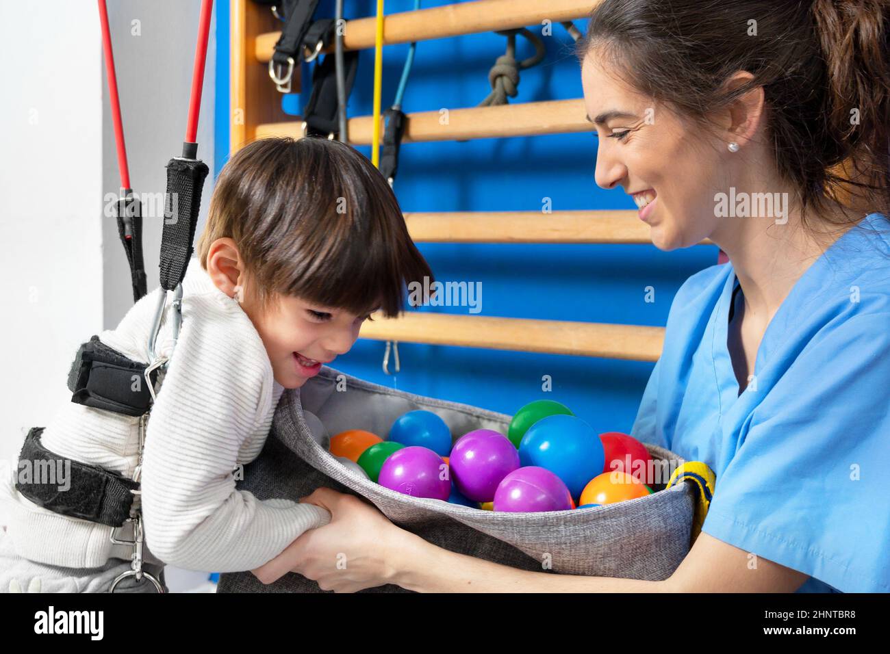 Cute kid with cerebral palsy doing musculoskeletal therapy in the hospital while laughing and having fun . Stock Photo