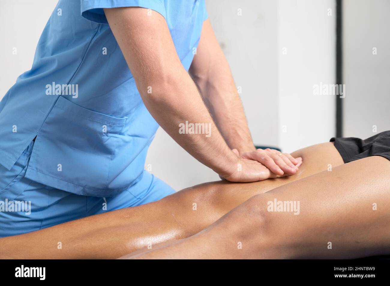Close-up of therapist massaging young man's leg Stock Photo