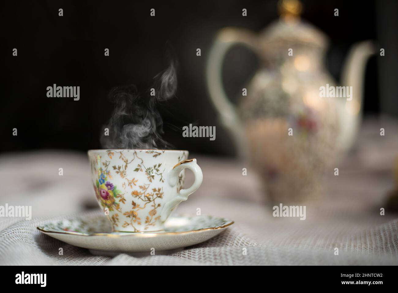 Porcelain tea pot and cup of hot tea on the table, antique traditional