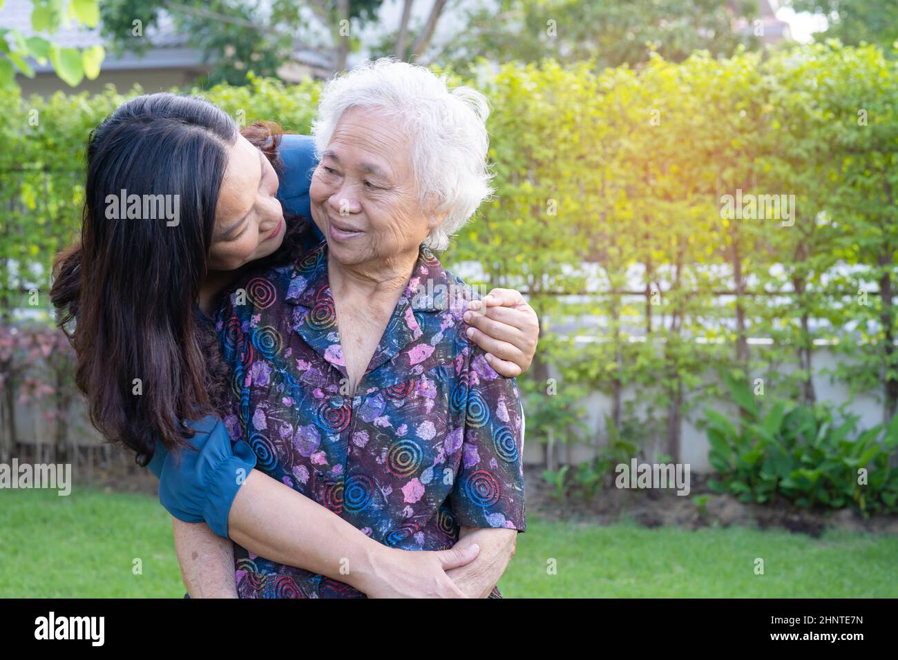 Asian elderly woman with caregiver walking with happy in nature park. Stock Photo