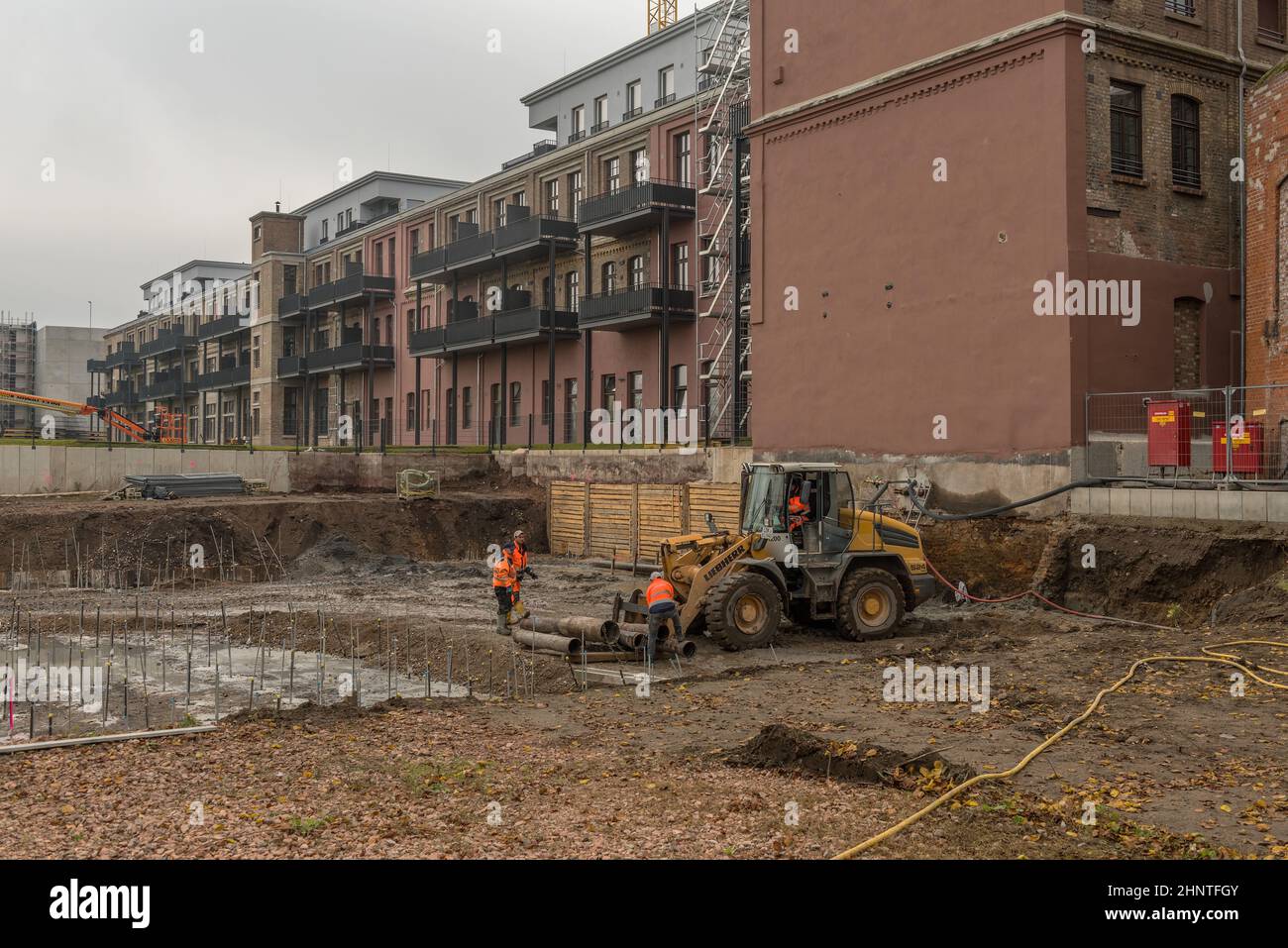 Construction workers loading old pipes on a large construction site Stock Photo