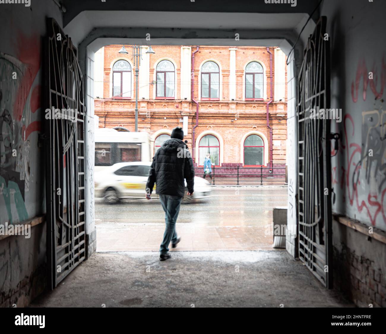 26th of October 2020, Russia, Tomsk, man go outside from arch to street Stock Photo