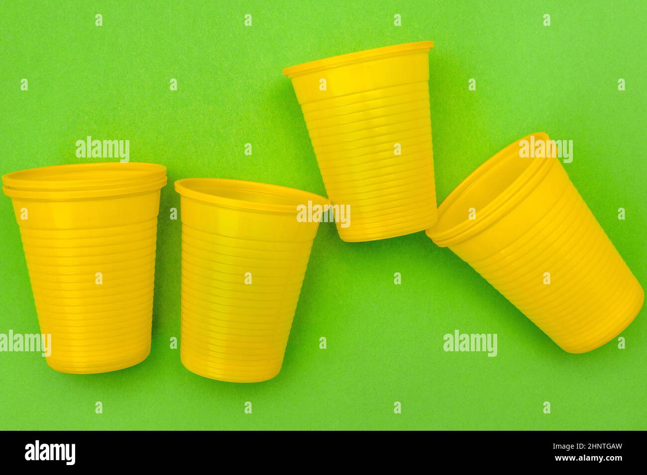 Empty disposable yellow plastic cups on the green background Stock