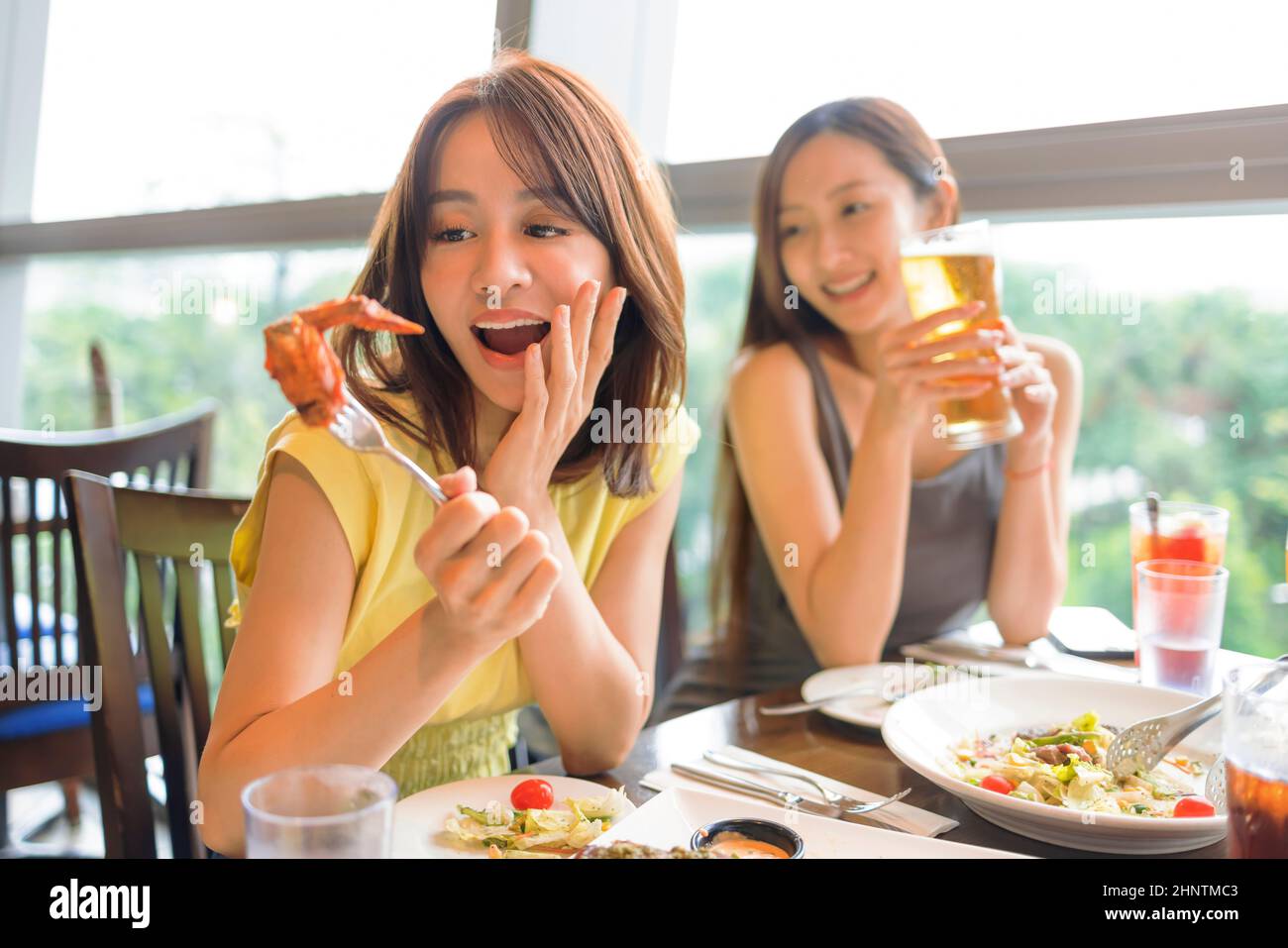 Happy  young woman enjoying food and drink in restaurant Stock Photo