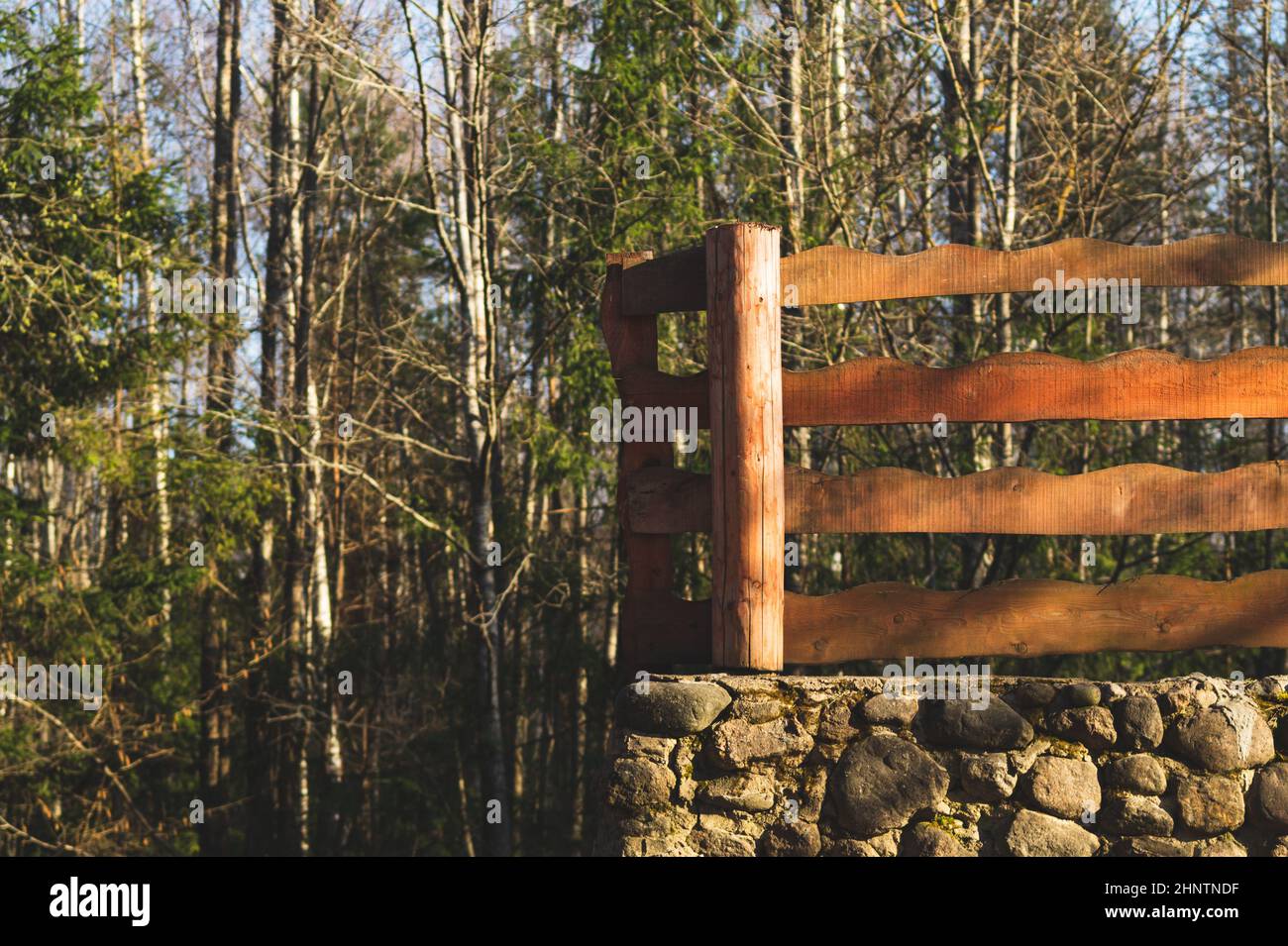 Trees in the park. wooden fencing and natural stone wall. nature background Stock Photo Alamy