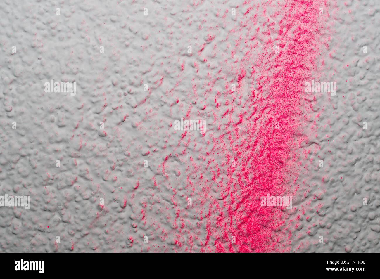 Uneven wall with red splashes of paint. rough surface. painted concrete