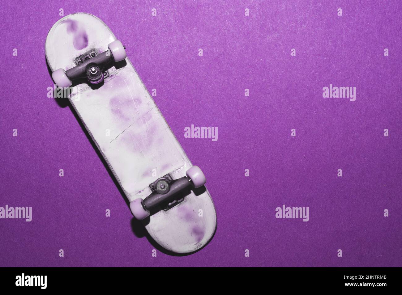 Small skateboard on purple background. tiny skate for fingers