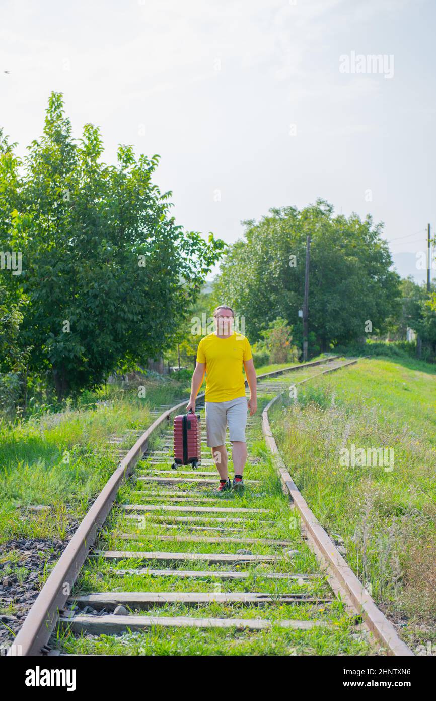 happy man with suitcase walking on the railroad Stock Photo