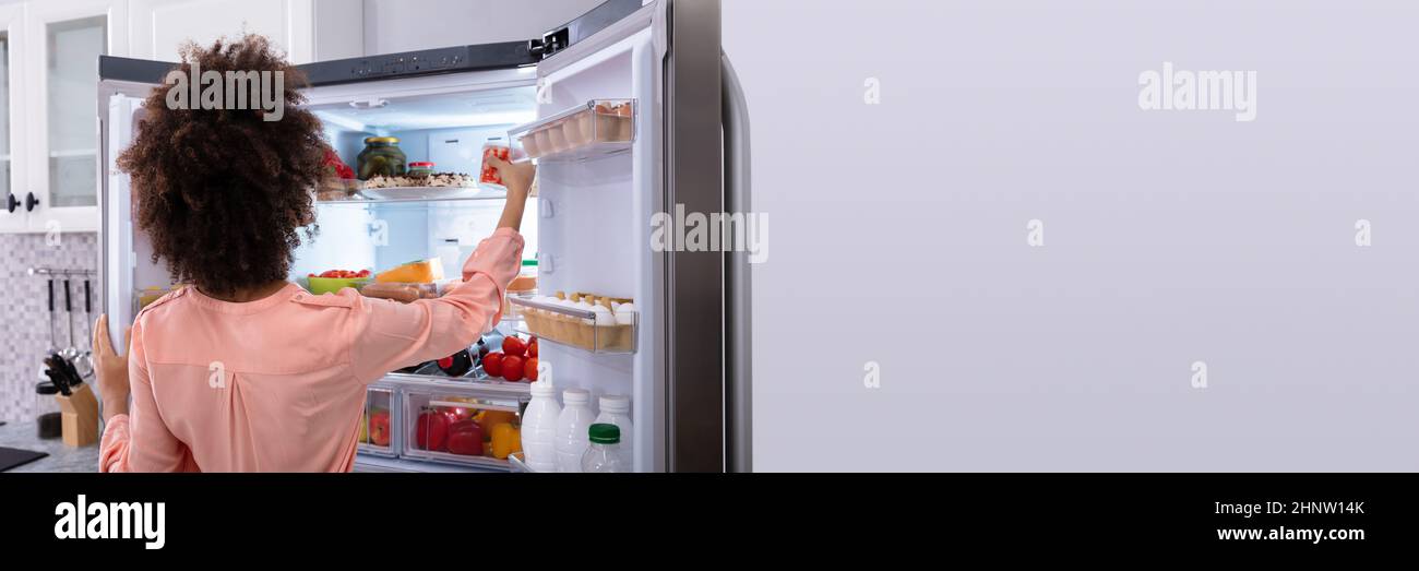 Hungry Woman Eating From Fridge. Lady Taking Healthy Food Stock Photo