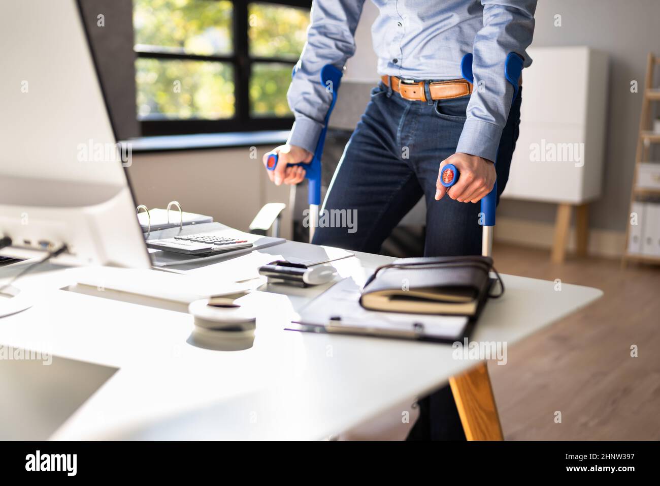 Worker With Crutches At Workplace Or Office. Rehabilitation Benefits