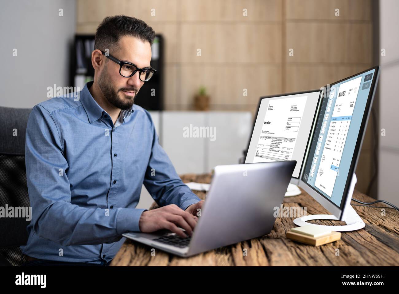 Looking At Invoice And Spreadsheet On Computer At Work Stock Photo