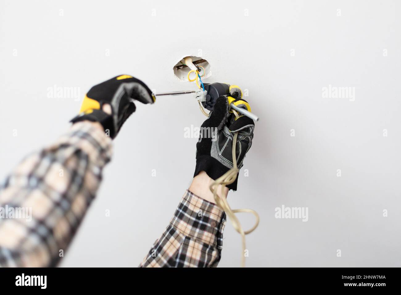 electrician repairing electrical wiring of ceiling lamp at home Stock