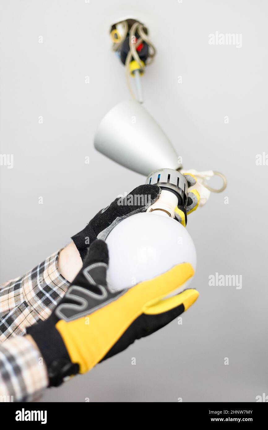 electrician remove bulb from defective ceiling light at home Stock Photo
