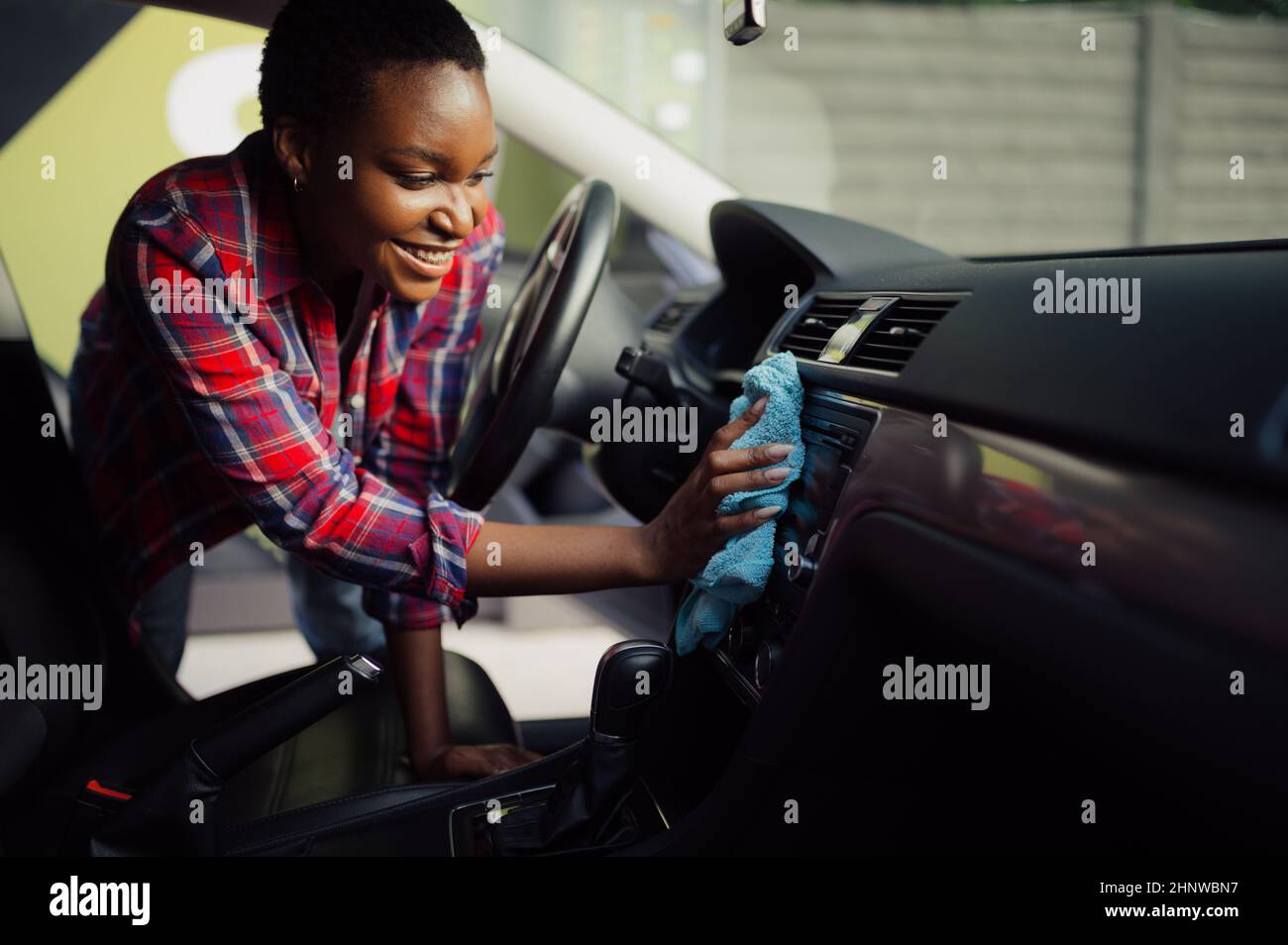 Woman wipes car interior with a rag, hand auto wash station. Carwash