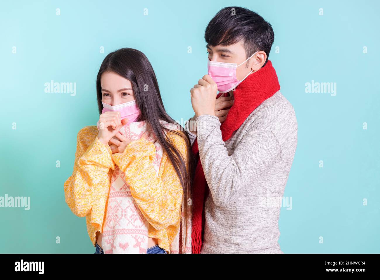 Young couple wearing scarves and medical masks, making cold and coughing gestures. Isolated on