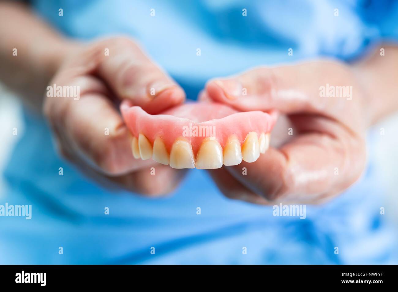 Asian senior or elderly old woman patient holding to use denture in