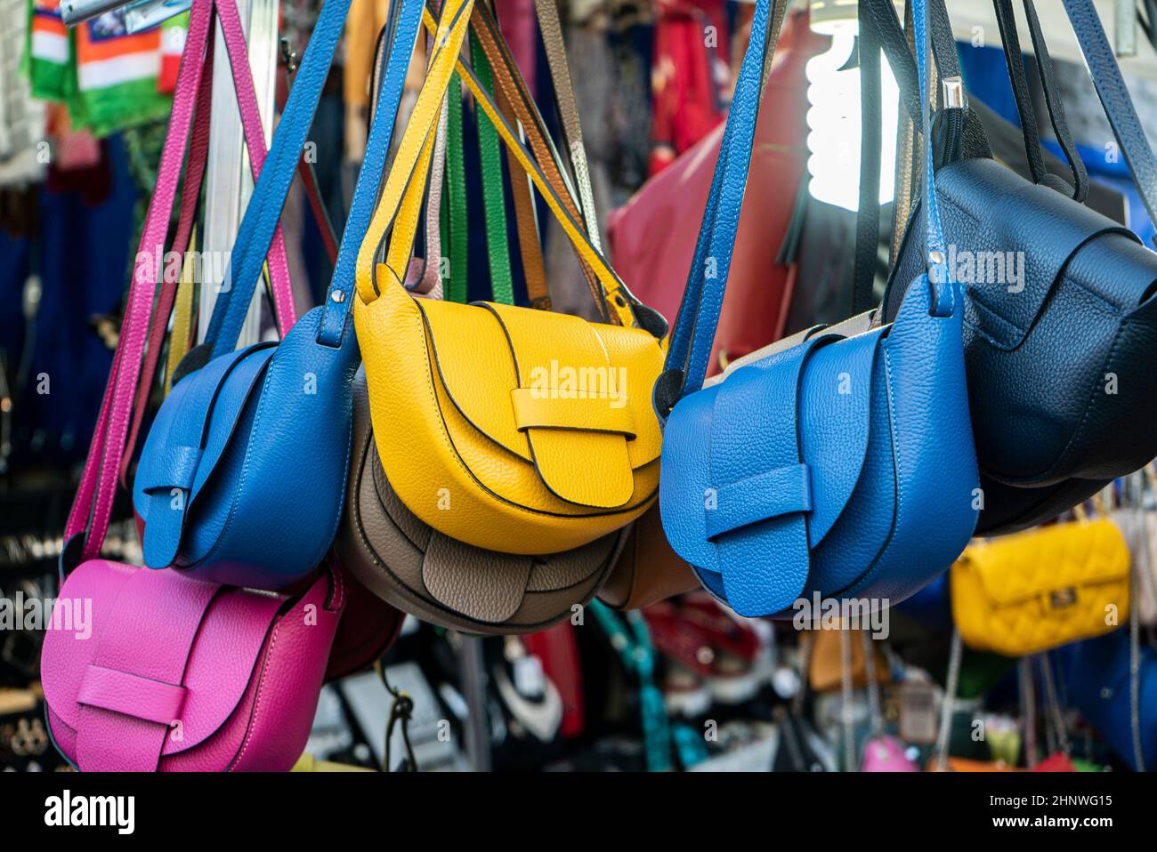 many leather purse bags vibrant colors hanging on display in shopping street market 2HNWG15
