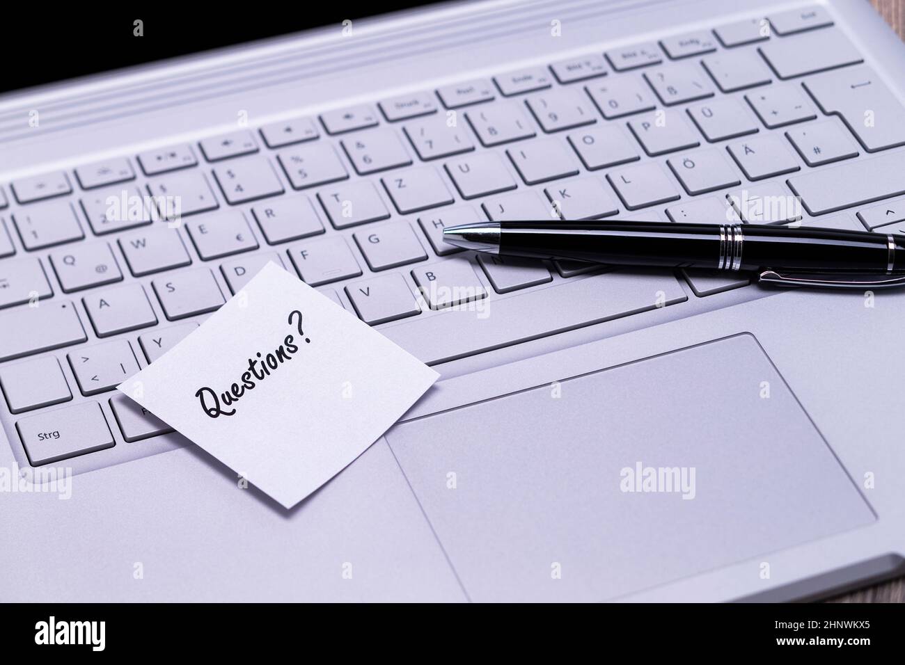 The photo shows a note with the text questions on a notebook computer ...