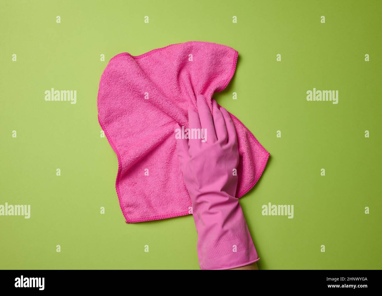 hand in a pink rubber glove holds a soft rag for cleaning surfaces on a ...