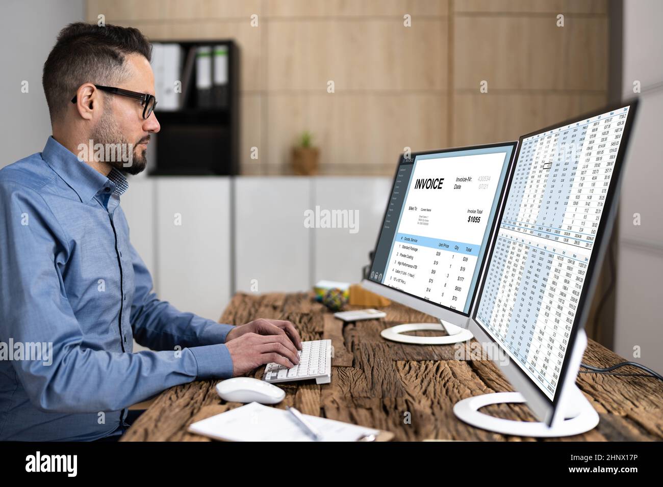 Looking At Invoice And Spreadsheet On Computer At Work Stock Photo